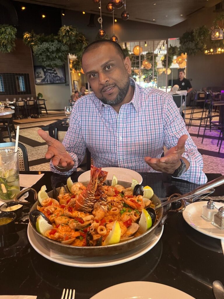 "Ramesh Patel" eating dinner at a fancy restaurant spending the money he allegedly scammed from people.
